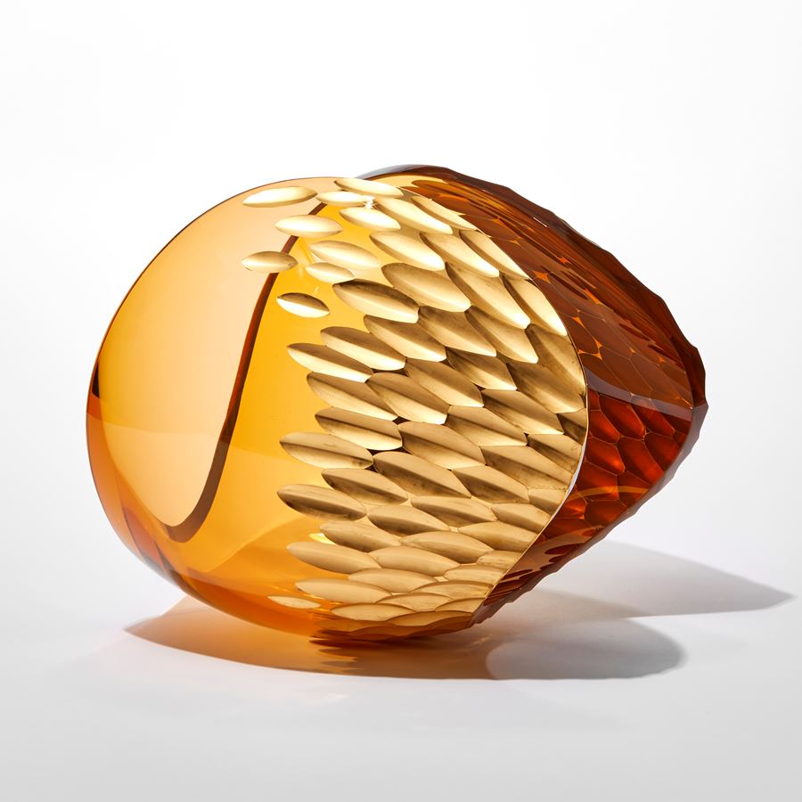 rich amber peach transparent ovoid sculpture with sweeping cut away section creating a curved traversing rim with repeat leaf shaped patterned incised section in gold hand made from glass